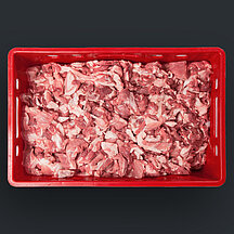 Rote Transportkiste mit Schweinefleischabschnitten vor dunklem Hintergrund.