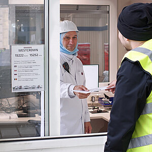 Mitarbeiter von WestCrown übergibt an einem Fenster Dokumente an eine Person im Rampenmanagement.