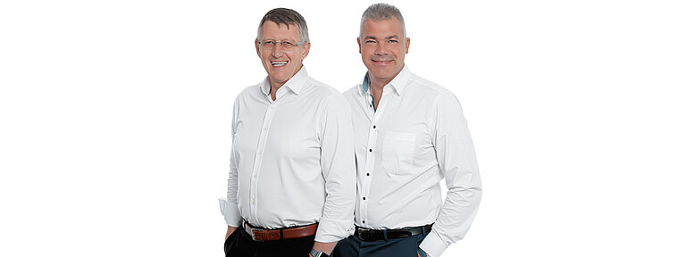 Porträt der beiden WestCrown-Geschäftsführer in weißen Hemden vor hellem Hintergrund.