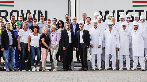 WestCrown-Team vor zwei Lkw mit großem Markenlogo auf den Aufliegern.